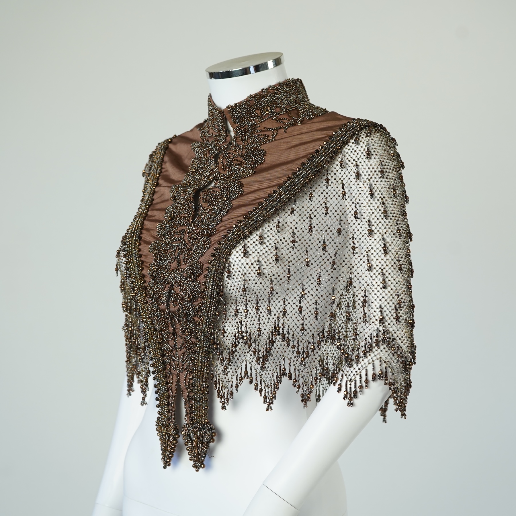 A late 19th century ladies ornate steel and brown beaded and fringed shoulder cape. Made as three ribbed silk panels with ornate beaded appliqués with a beaded and fringed net sleeved cape. Top of neck to bottom of beadi